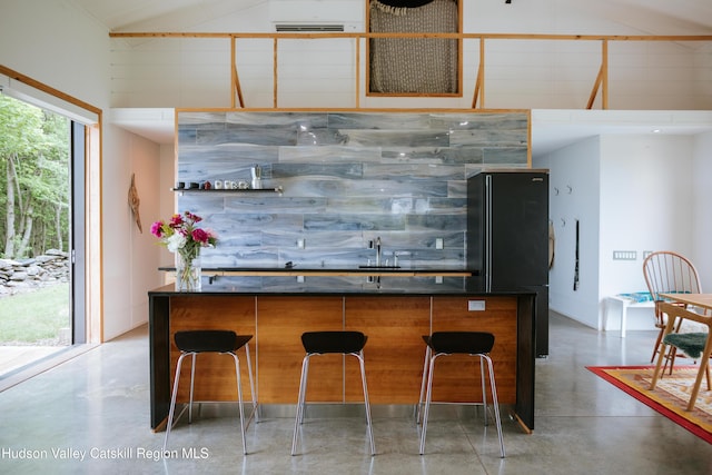 1199 W Highland Rd, Hobart, NY 13788 - kitchen with concrete flooring, high vaulted ceiling, dark countertops, freestanding refrigerator, and a center island