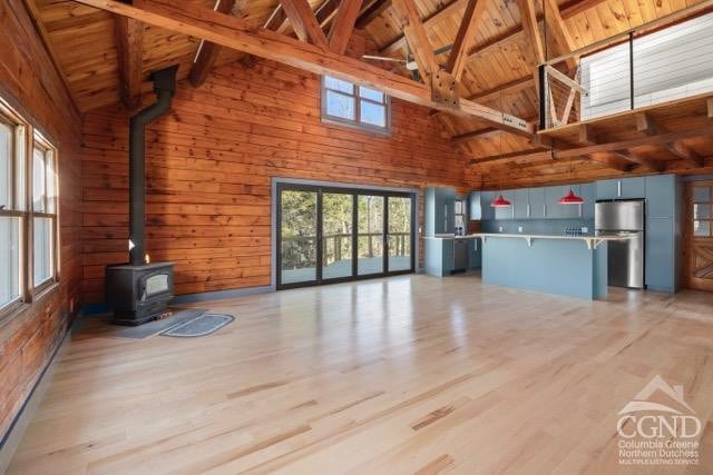 269 Church Ave, Germantown, NY 12526 - unfurnished living room with high vaulted ceiling, wood ceiling, a wood stove, wooden walls, and light wood-style floors