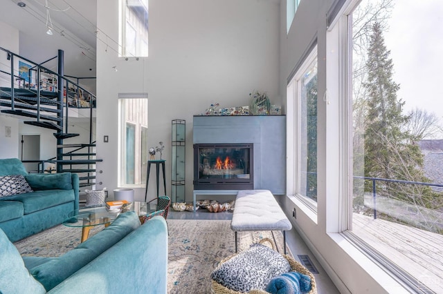 219 Sleepy Hollow Rd, Athens, NY 12015 - living room featuring stairway, a high ceiling, a glass covered fireplace, and wood finished floors
