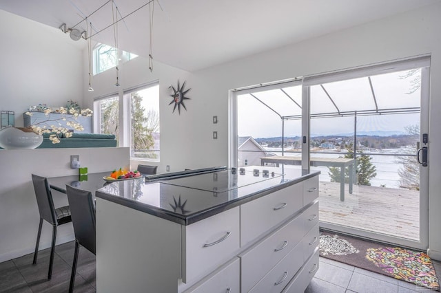 219 Sleepy Hollow Rd, Athens, NY 12015 - kitchen with black electric stovetop, white cabinetry, tile patterned floors, dark countertops, and a kitchen island