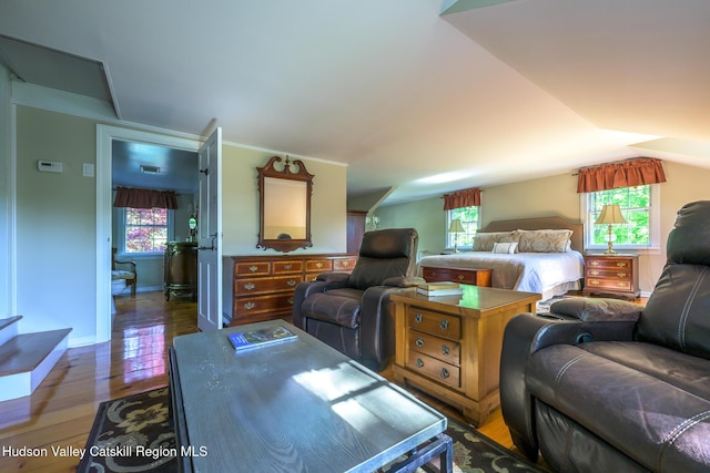 living room featuring light wood-type flooring, vaulted ceiling, crown molding, and baseboards
