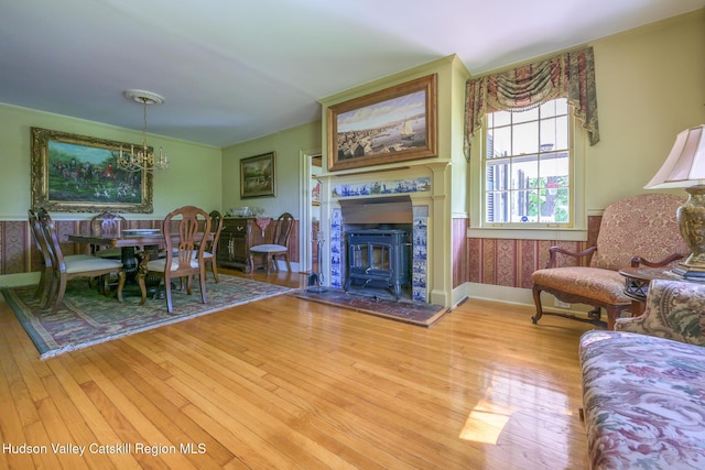 living room featuring light wood finished floors, a chandelier, baseboards, and wainscoting