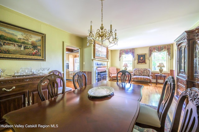 dining space with a chandelier, wood finished floors, wainscoting, and baseboard heating