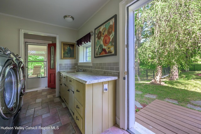 laundry room featuring a sink, stone tile floors, washer / clothes dryer, and ornamental molding