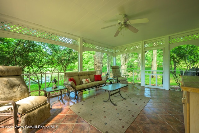 sunroom featuring a ceiling fan, an outdoor living space, and tile patterned floors