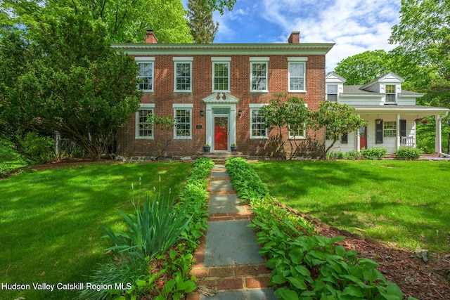 view of front facade with a chimney, a front lawn, and brick siding
