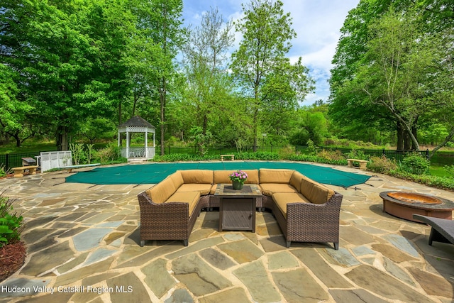 view of swimming pool featuring a gazebo, an outdoor living space with a fire pit, a diving board, a patio, and view of scattered trees