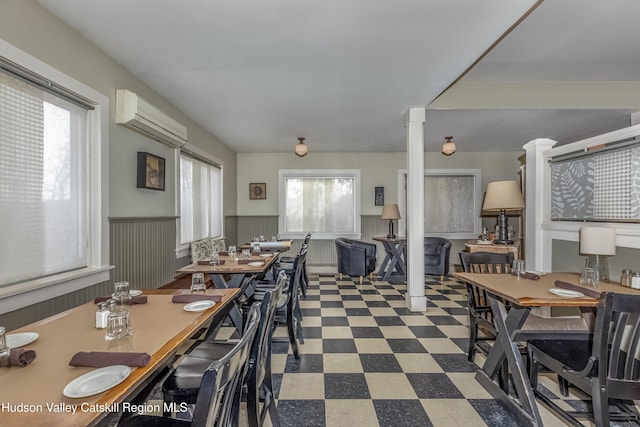 dining room featuring ornate columns, tile patterned floors, a wall unit AC, and wainscoting
