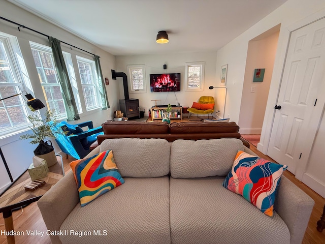 living area with a wood stove, baseboards, and wood finished floors