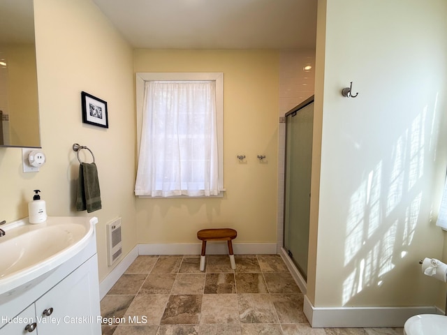 full bath with heating unit, a stall shower, vanity, and baseboards