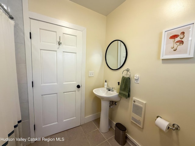 bathroom with curtained shower, tile patterned floors, heating unit, and baseboards