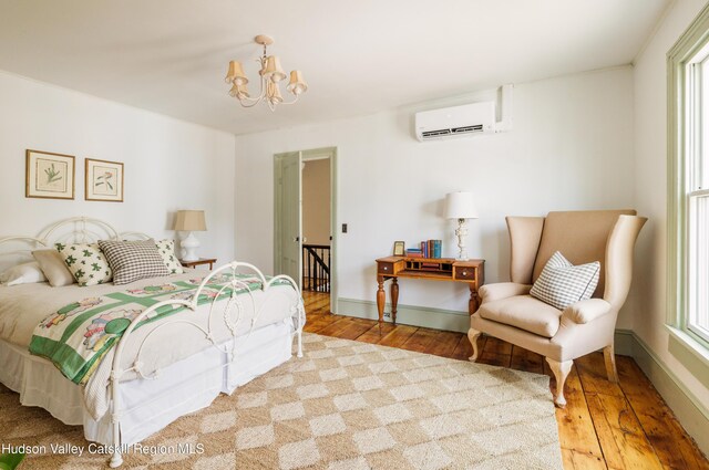225 Robinson St, Hudson, NY 12534 - bedroom featuring an AC wall unit, hardwood / wood-style floors, and a chandelier