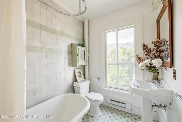 225 Robinson St, Hudson, NY 12534 - bathroom featuring baseboard heating, a soaking tub, plenty of natural light, and tile walls