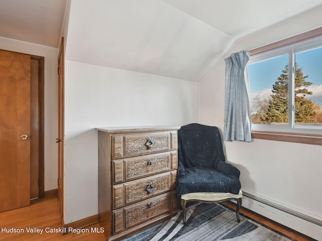 living area with a baseboard radiator, lofted ceiling, and hardwood / wood-style flooring