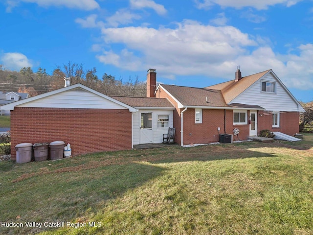 rear view of property featuring central air condition unit and a yard