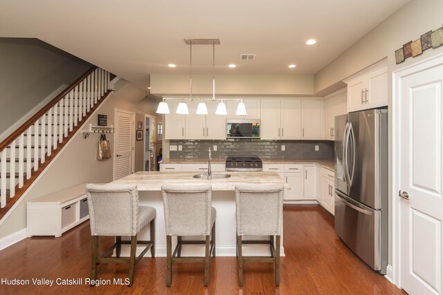 208 Hudson View Ter, Hyde Park, NY 12538 - kitchen featuring appliances with stainless steel finishes, decorative backsplash, white cabinets, a center island with sink, and pendant lighting