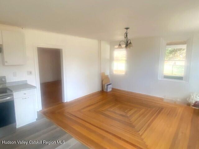 unfurnished dining area with wood-type flooring and a notable chandelier