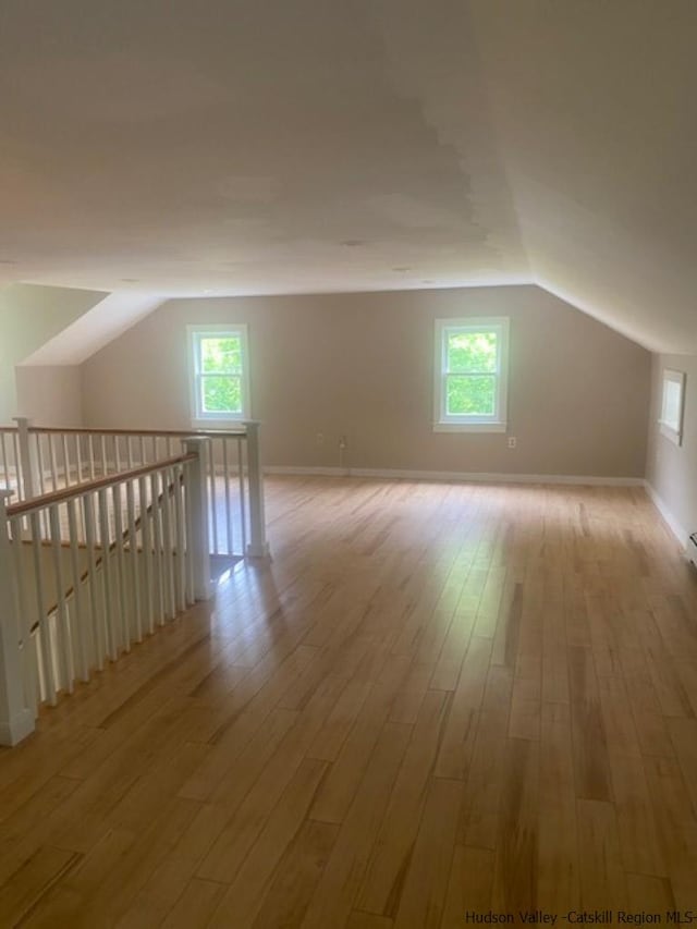 bonus room with a wealth of natural light, lofted ceiling, and light wood-type flooring