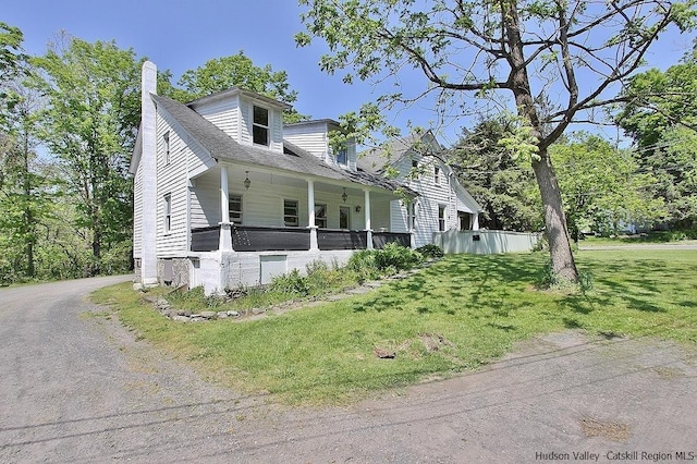 cape cod-style house featuring covered porch and a front yard