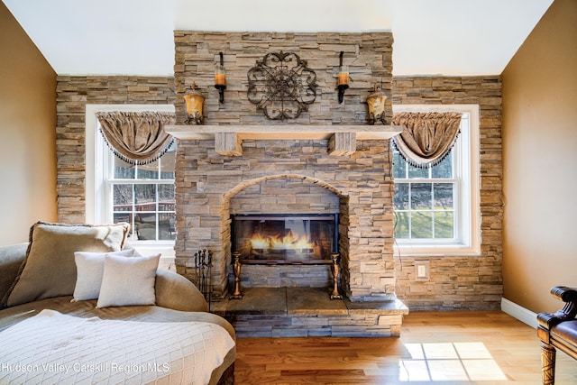 bedroom with baseboards, wood finished floors, and a fireplace