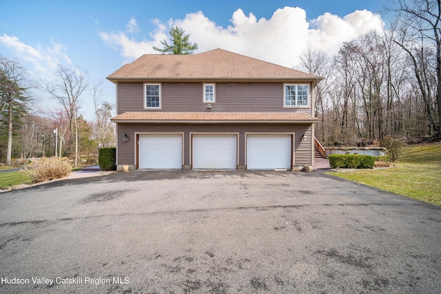 view of home's exterior featuring stairs, an attached garage, driveway, and a shingled roof