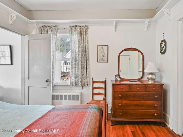 bedroom with radiator heating unit and hardwood / wood-style flooring