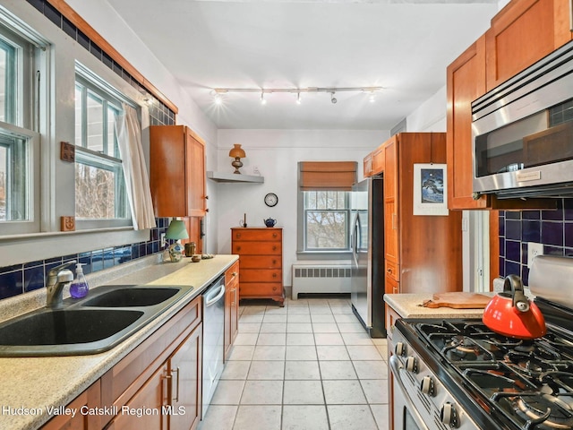 kitchen featuring a wealth of natural light, radiator, stainless steel appliances, sink, and light tile patterned floors