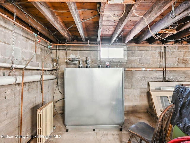 basement with stainless steel fridge and radiator heating unit