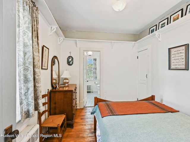 bedroom with hardwood / wood-style flooring, radiator heating unit, and connected bathroom