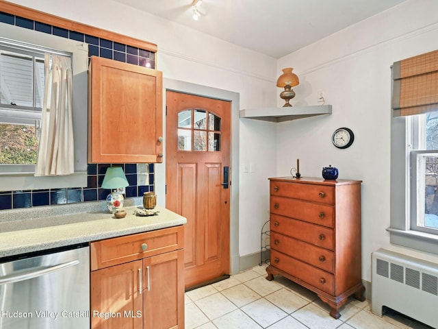 kitchen with tasteful backsplash, radiator, light tile patterned floors, and stainless steel dishwasher