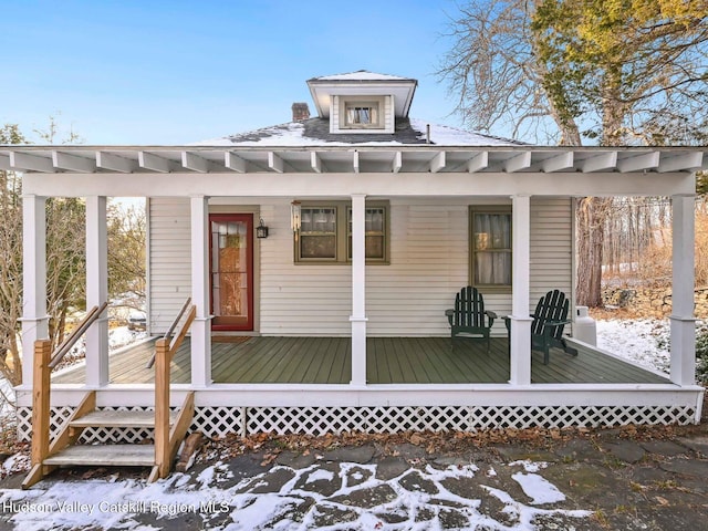 snow covered property with covered porch