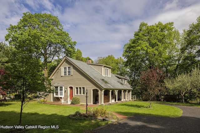 view of front of property featuring a chimney, a front yard, and a porch