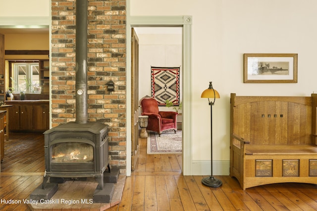 living area with a wood stove, hardwood / wood-style floors, and baseboards