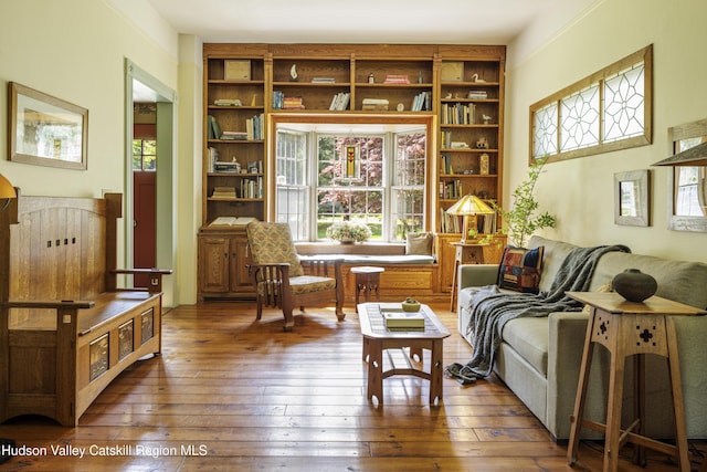 sitting room featuring hardwood / wood-style floors and built in shelves