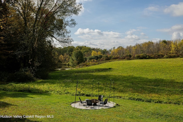 view of yard featuring a water view, a fire pit, and a patio area