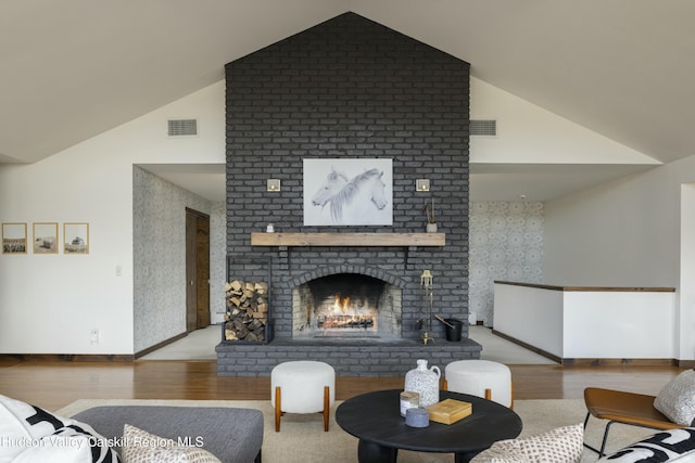 living room with light wood-type flooring, a fireplace, and vaulted ceiling