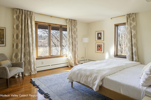 bedroom with a baseboard heating unit and hardwood / wood-style flooring