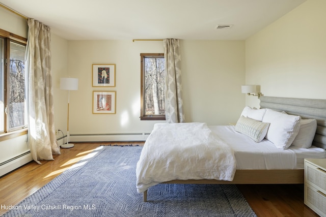 bedroom featuring hardwood / wood-style flooring and baseboard heating