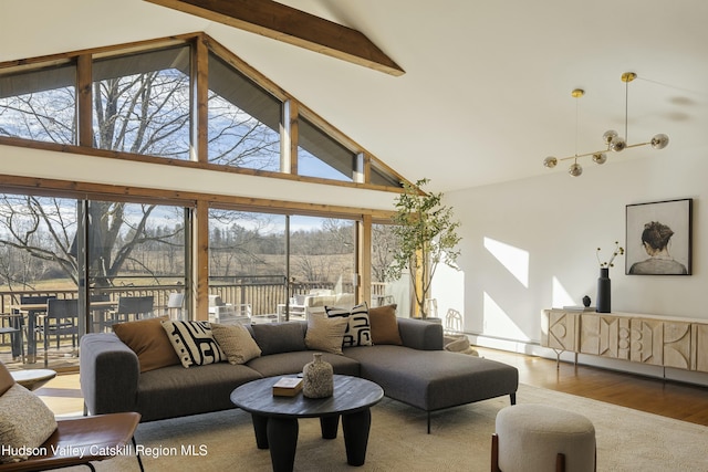 living room with hardwood / wood-style floors, high vaulted ceiling, a notable chandelier, and beam ceiling