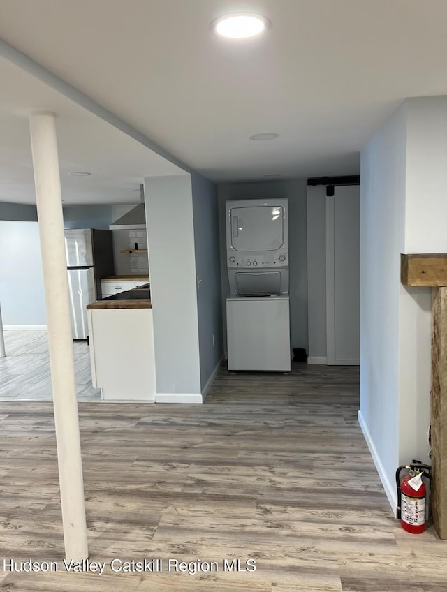 hall with hardwood / wood-style flooring and stacked washer / drying machine