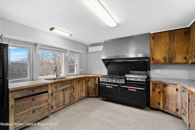 kitchen featuring sink, black fridge, a wall mounted air conditioner, range with two ovens, and exhaust hood