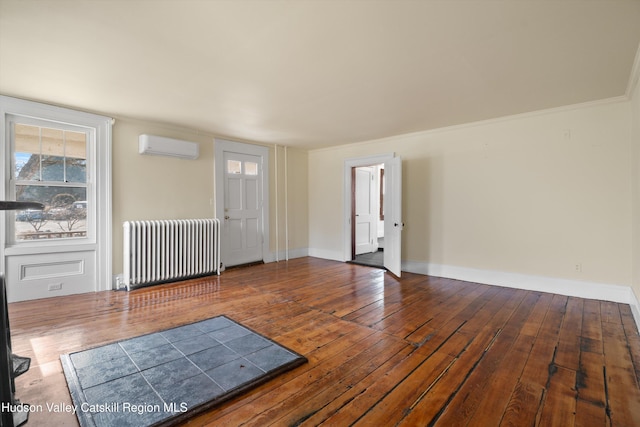 spare room featuring hardwood / wood-style flooring, crown molding, radiator, and a wall unit AC