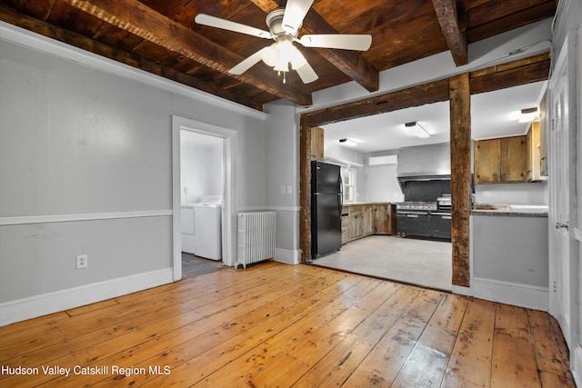 unfurnished living room with washing machine and clothes dryer, light hardwood / wood-style flooring, radiator, ceiling fan, and beam ceiling