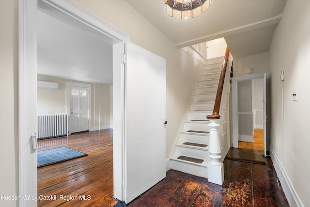 stairway with a wall mounted AC, wood-type flooring, and radiator heating unit