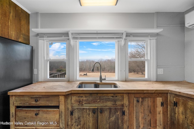 kitchen featuring butcher block counters, sink, a wall mounted air conditioner, and stainless steel refrigerator