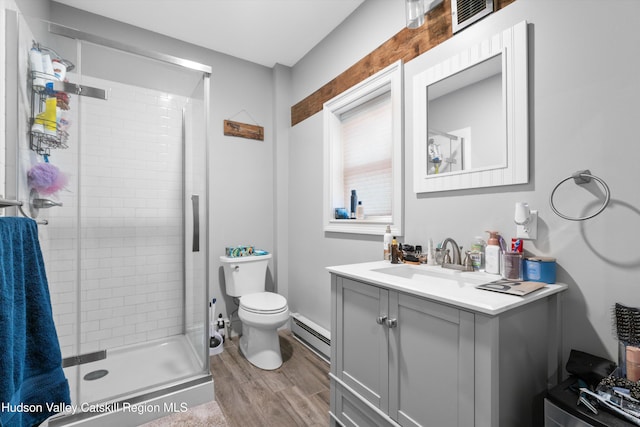 bathroom with a shower with door, a baseboard heating unit, hardwood / wood-style floors, vanity, and toilet