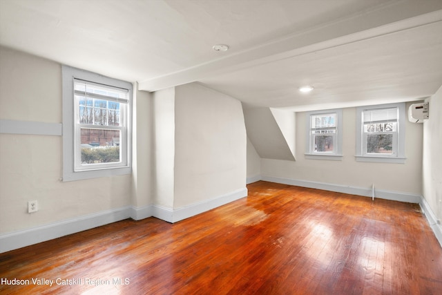 bonus room with wood-type flooring, vaulted ceiling, and a wall unit AC