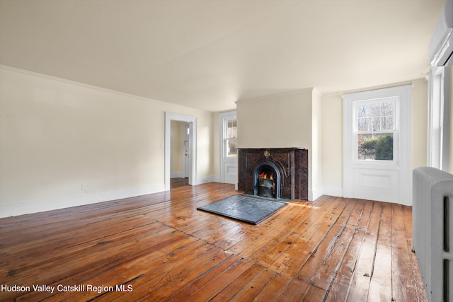 unfurnished living room featuring hardwood / wood-style flooring and crown molding