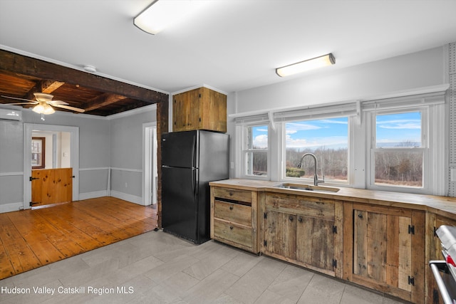 kitchen featuring sink, ceiling fan, black refrigerator, an AC wall unit, and beamed ceiling