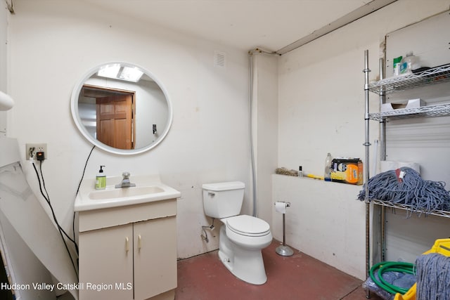 bathroom with concrete flooring, vanity, and toilet